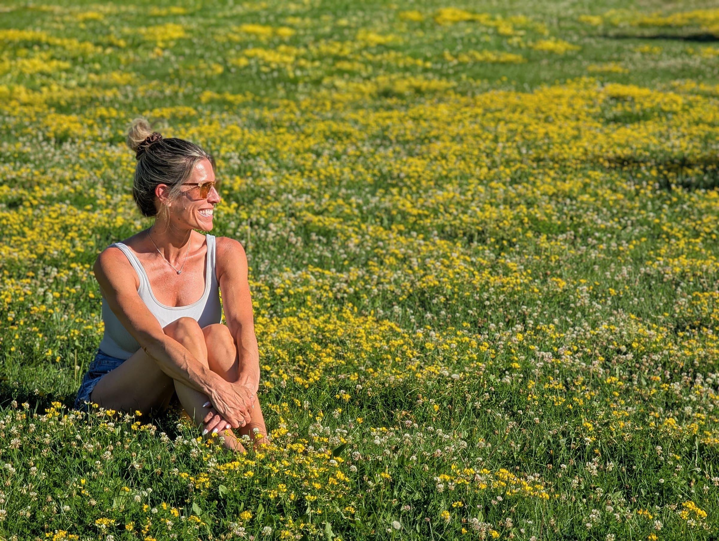Awbria sitting in a sunlit field of wildflowers